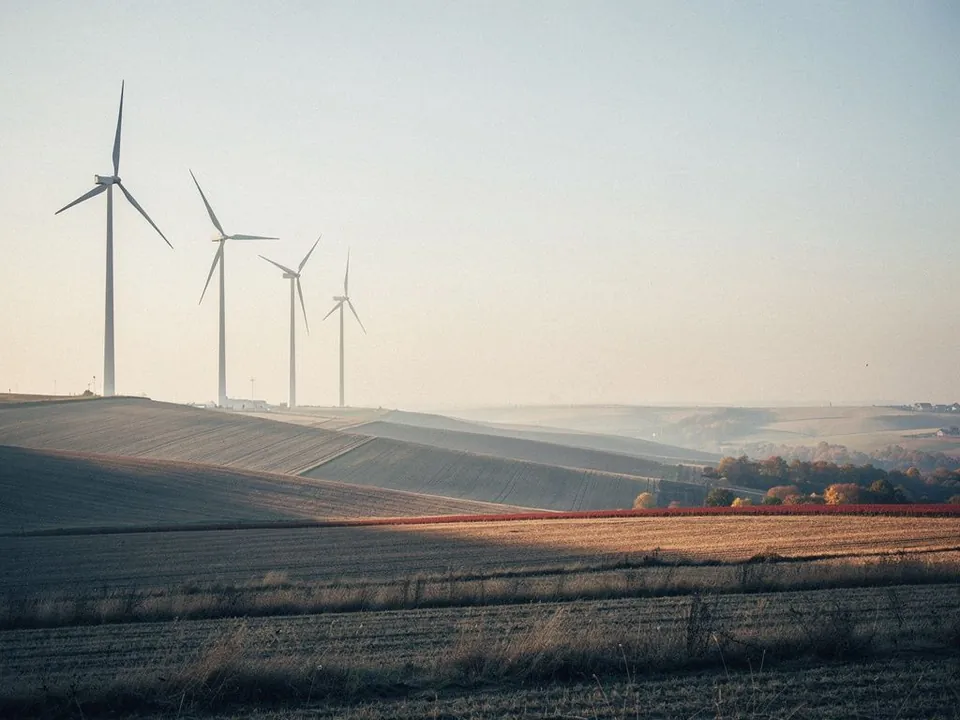 Wind turbines on a hillside at sunrise above autumn fields