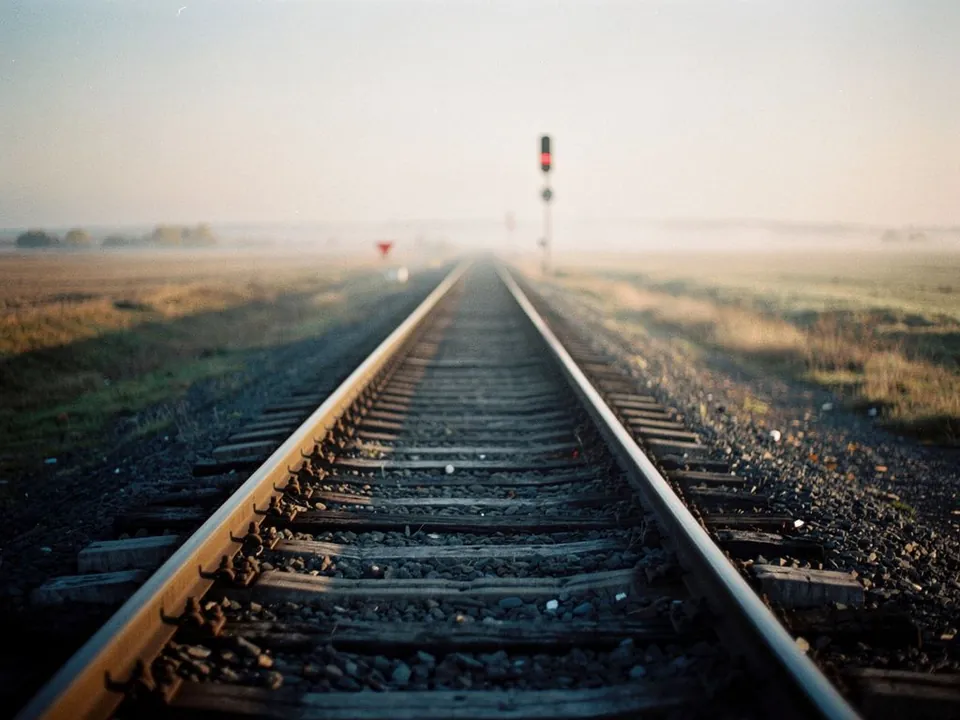 Railway tracks stretching across a wide plain at dawn