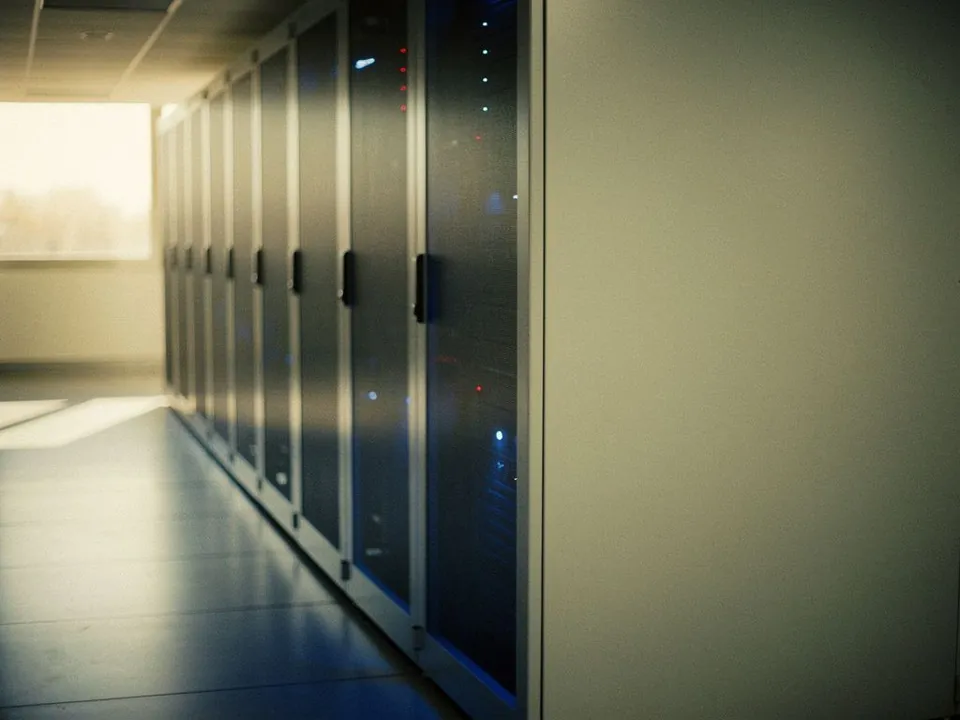Quiet data centre aisle with closed server racks and soft blue reflections
